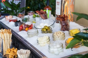 A buffet with various food items like fruits, cheeses, and meats displayed on ice.