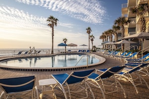 Una piscina al aire libre, camas de piscina con cargo, sombrillas