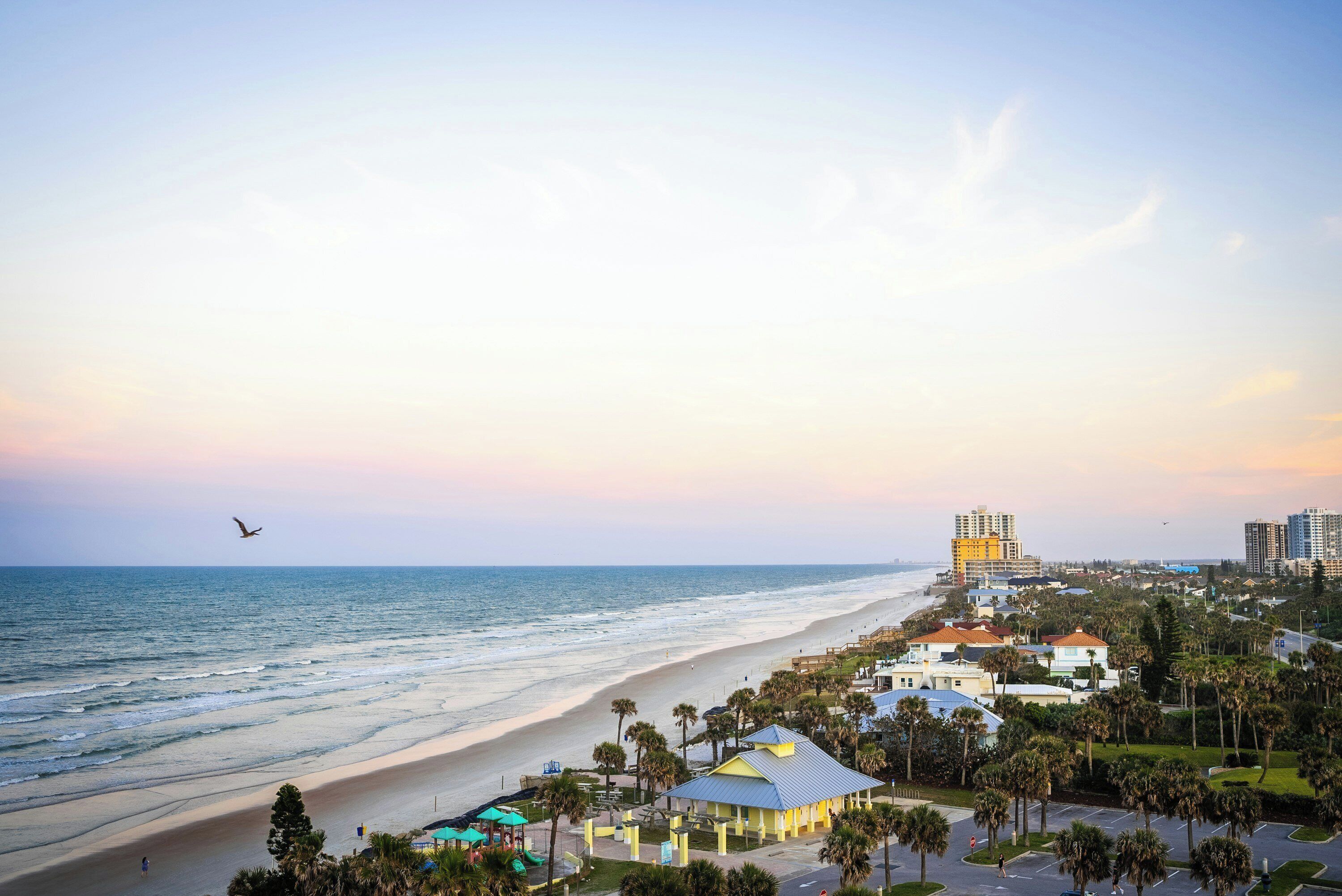 A coastal view with a beach, a playground, and residential buildings.