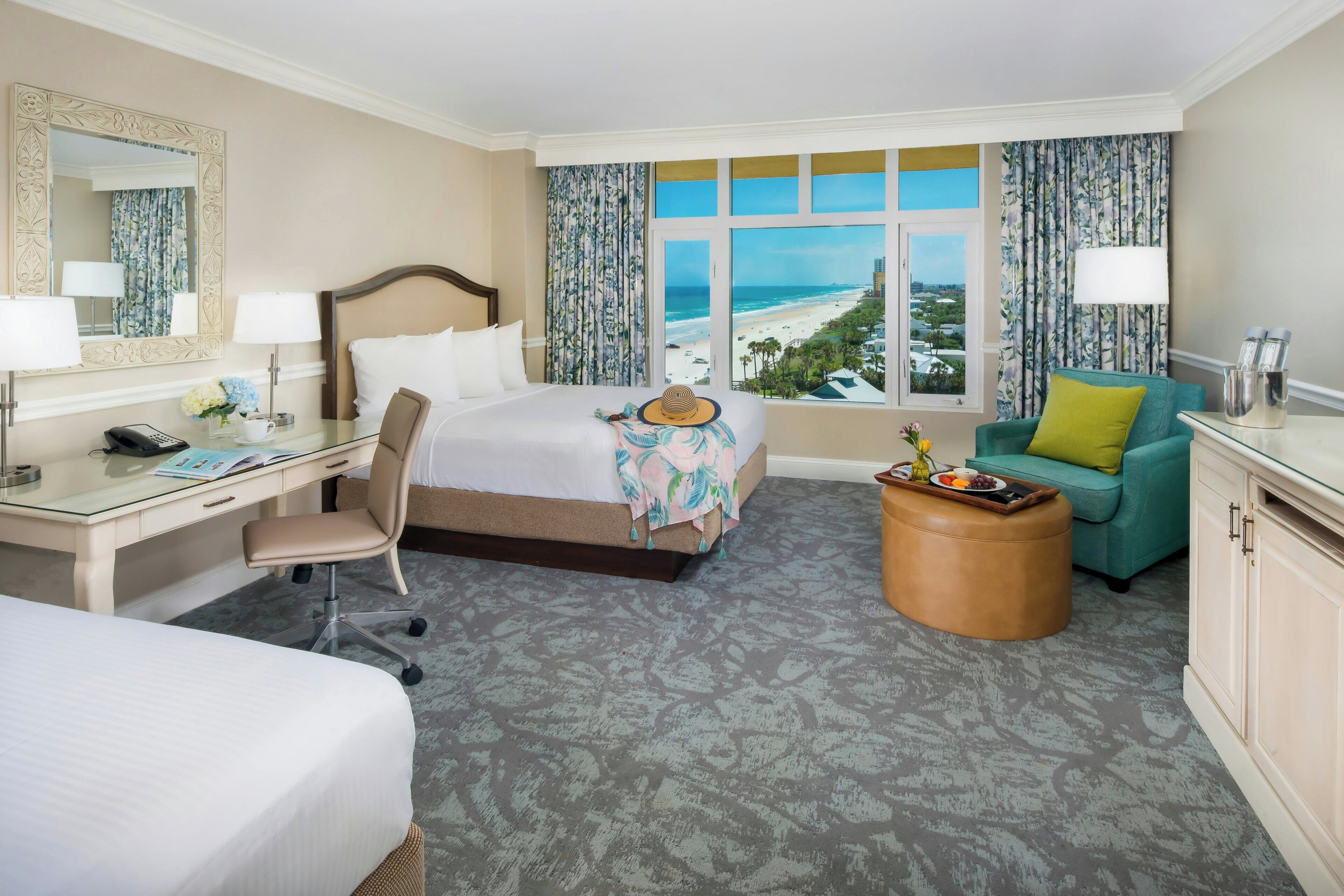 Habitación de hotel con cama, escritorio, silla y vista al mar.