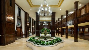 Un lobby espacioso con una fuente central, techos altos y paneles de madera elegantes.