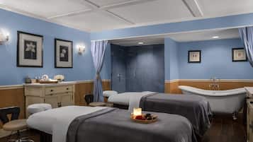 Relax in a serene spa room with two beds, a bathtub, and a cozy seating area.