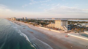 Un hotel frente al mar con vista a la playa, varios edificios de gran altura y un estacionamiento.
