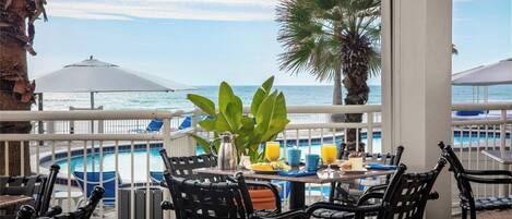 Zona junto a la piscina con mesa dispuesta para el desayuno, con vistas a la piscina y al océano.