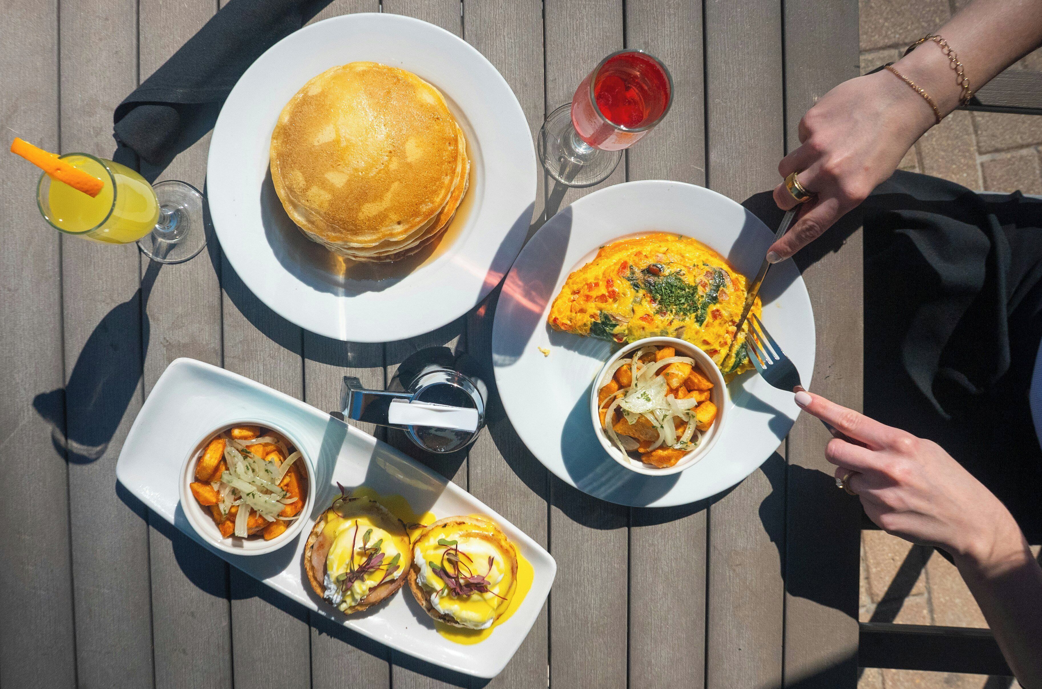 A table with breakfast items including pancakes, eggs, and a drink.