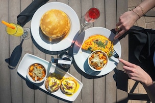 A table with breakfast items including pancakes, eggs, and a drink.