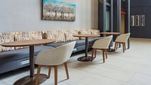 A modern seating area with a sofa and three round tables, each with a chair.
