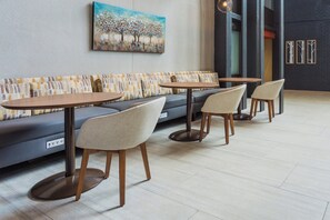 A modern seating area with a sofa and three round tables, each with a chair. - Holiday Inn Roanoke Airport – Conference CTR by IHG (Roanoke)