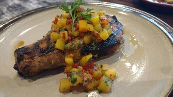 A plate with grilled meat and a pineapple salsa garnish.