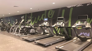 A gym with multiple treadmills and stationary bikes, a wall with motivational text, and a digital screen displaying workout content. - Holiday Inn Roanoke Airport – Conference CTR by IHG (Roanoke)