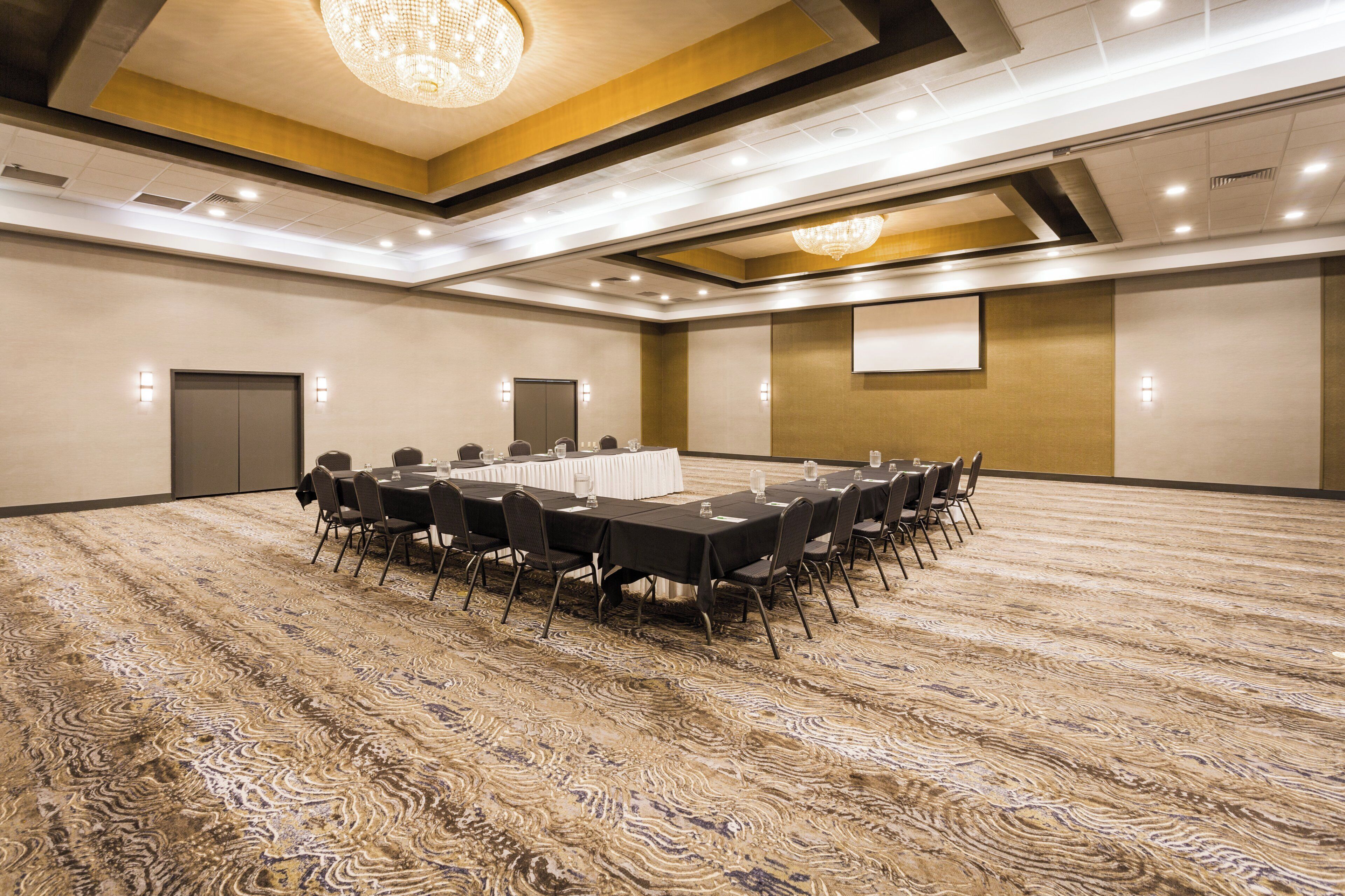Un salón de conferencias con una larga mesa, sillas y piso alfombrado.