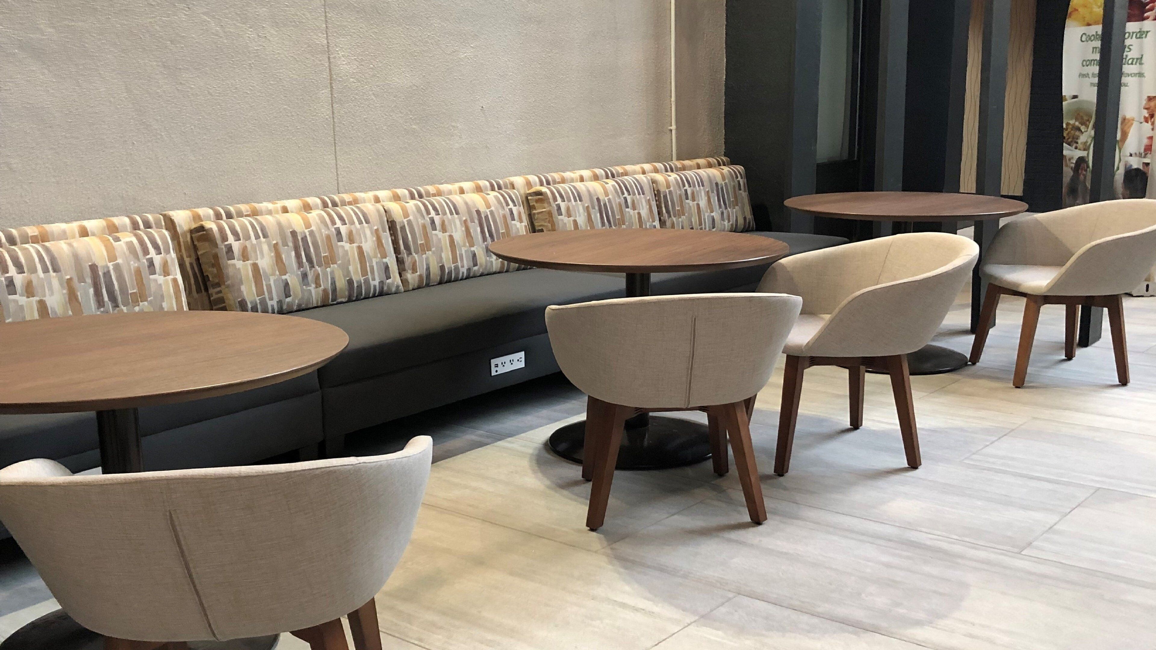 A modern seating area with a sofa and round tables, suitable for dining or socializing.