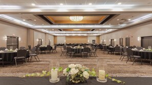 Une salle de conférence équipée de tables rondes, de chaises et d’un lustre.