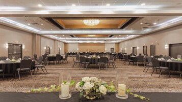 Un salón de conferencias con mesas redondas, sillas y una araña.
