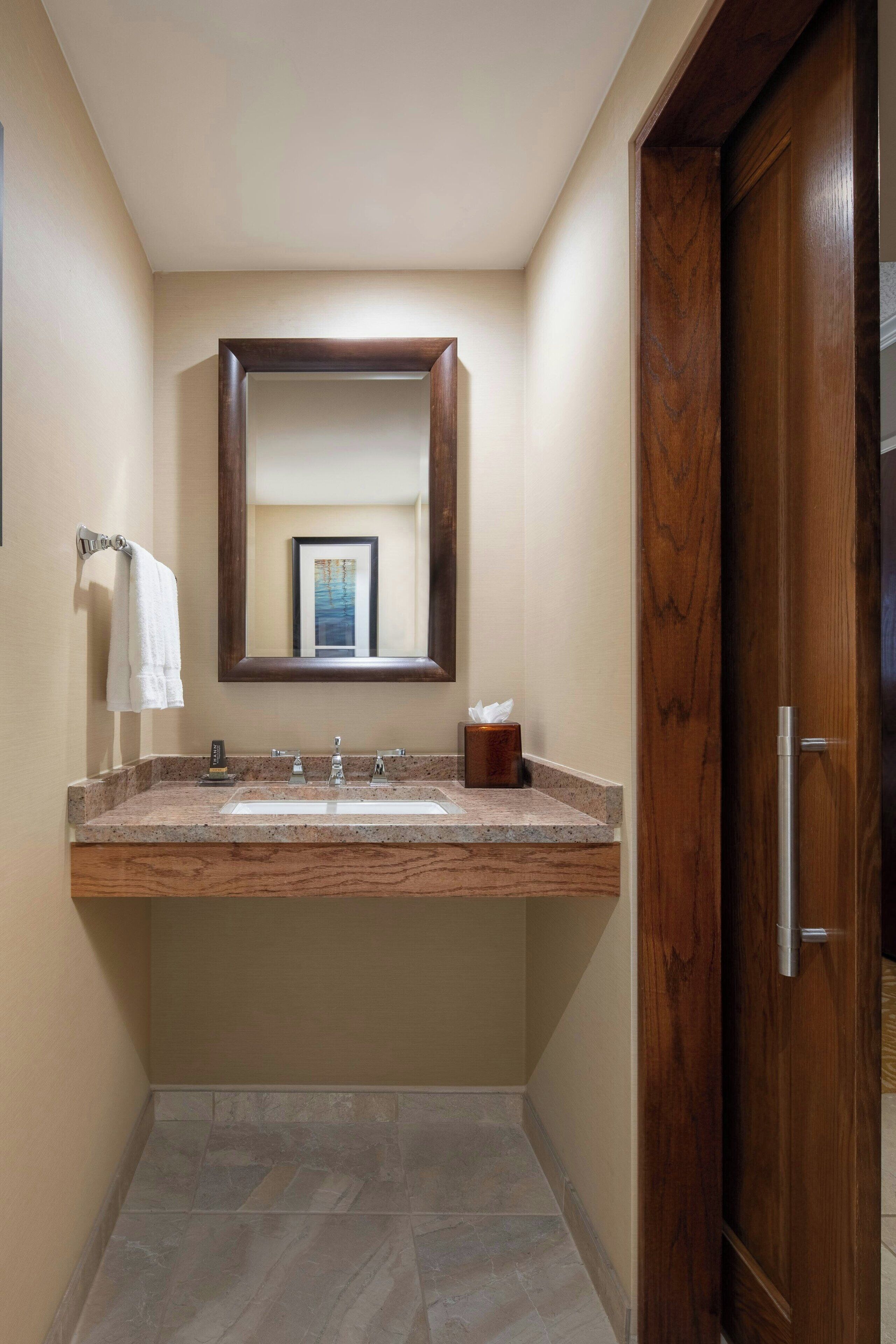 A bathroom with a large mirror, a sink, and a wooden door.