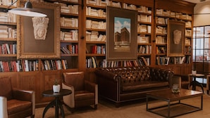 A library with leather sofas, bookshelves, and framed artwork.