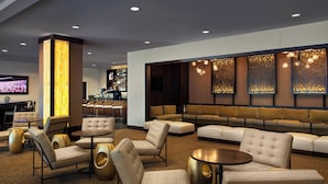 A modern lounge area with sofas, armchairs, and a bar.