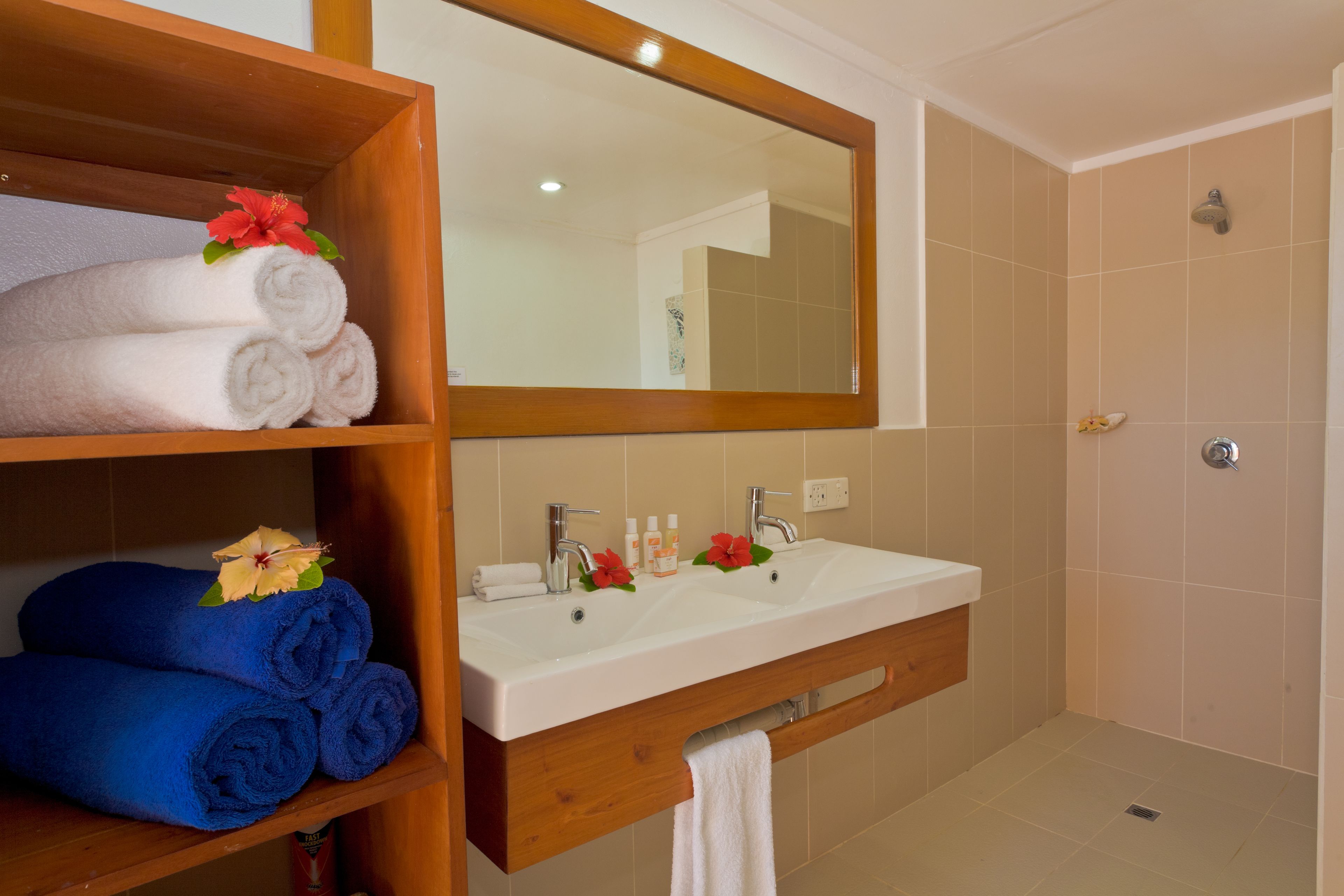 Un baño con tocador de madera, un espejo grande y zona de ducha.