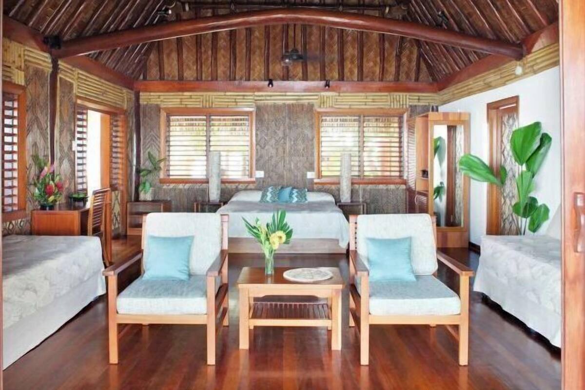 Une pièce spacieuse avec un grand lit, deux canapés, une table basse en bois et un plafond doté de poutres apparentes.
