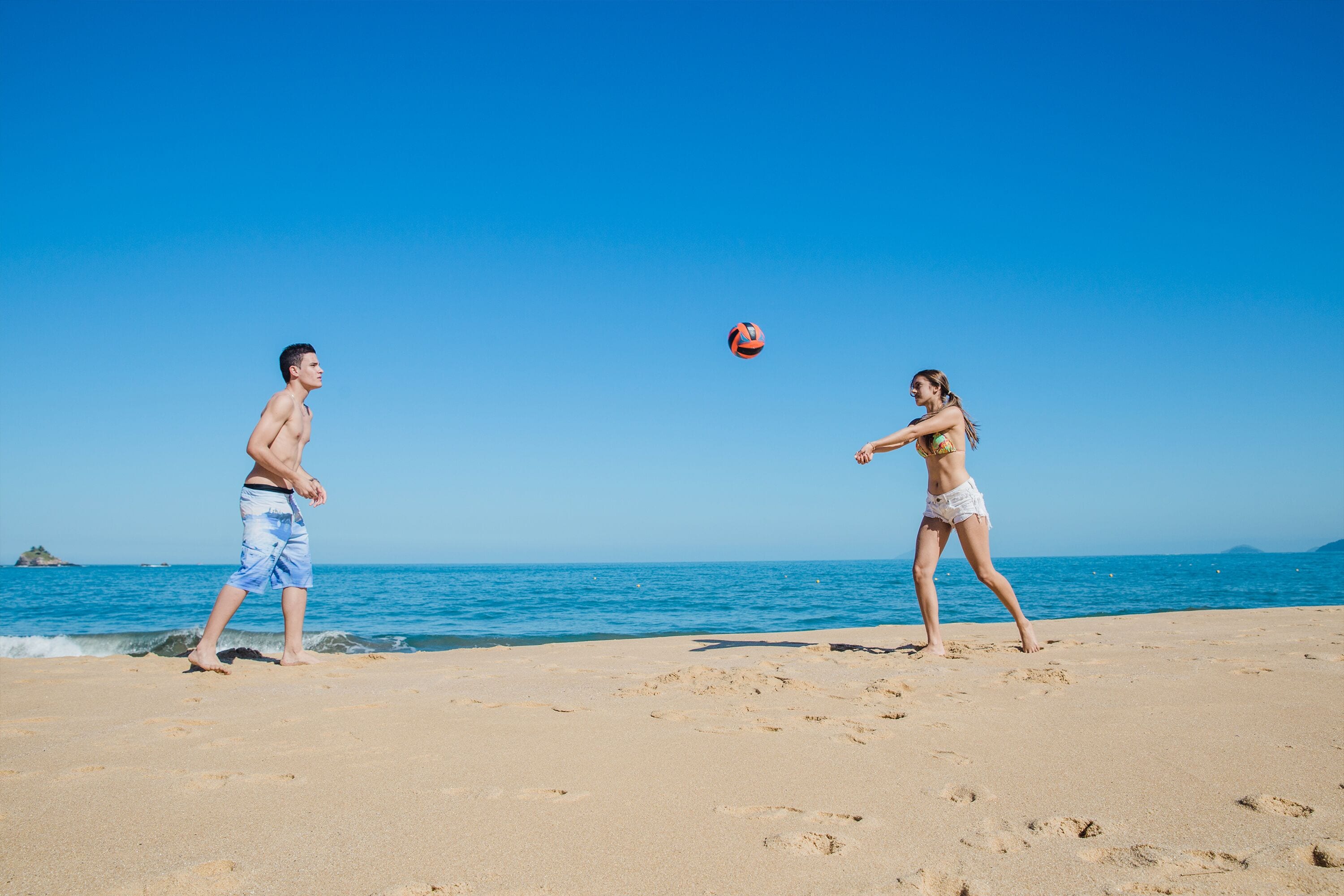 Una playa con un partido de voleibol en desarrollo.