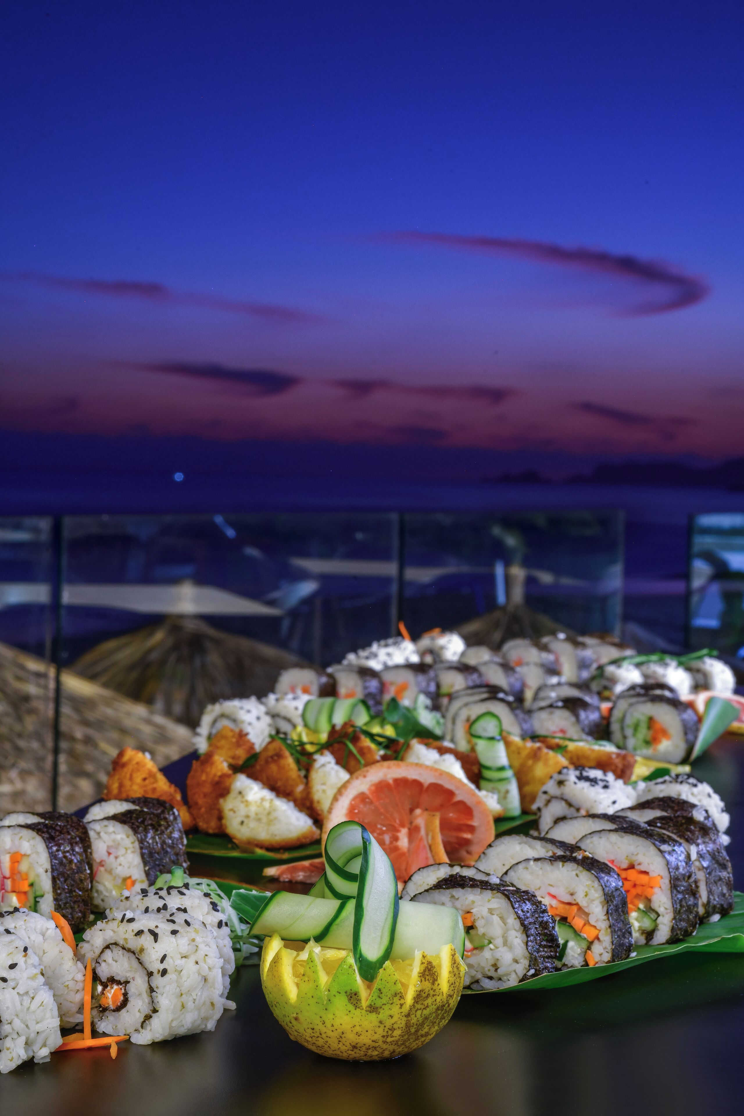 Eine Sushi-Platte mit verschiedenen Sushi-Sorten, darunter Nigiri und Rollen, präsentiert auf einem grünen Blatt.