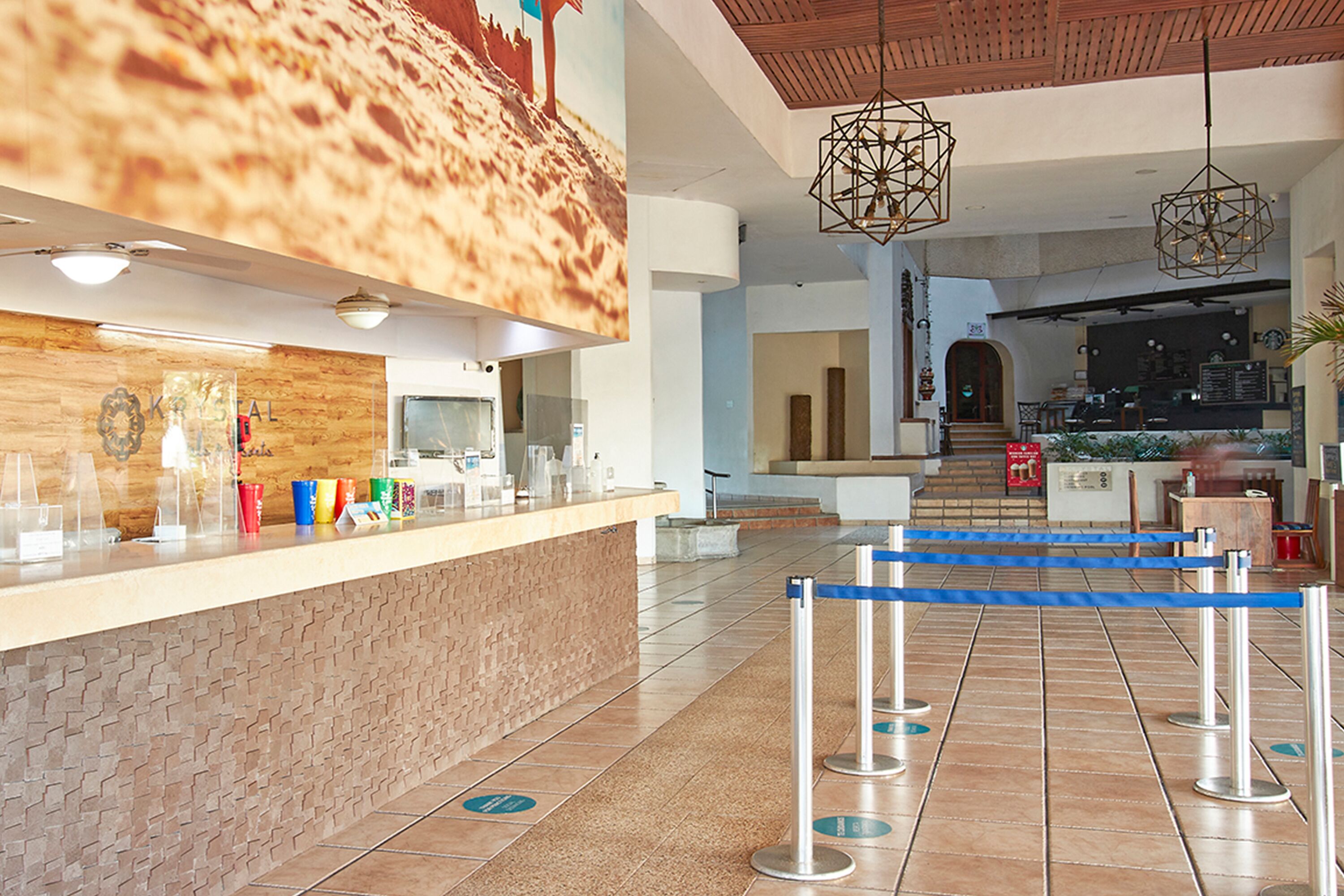 A hotel lobby with a reception desk, a staircase leading to the upper floor, and a seating area.