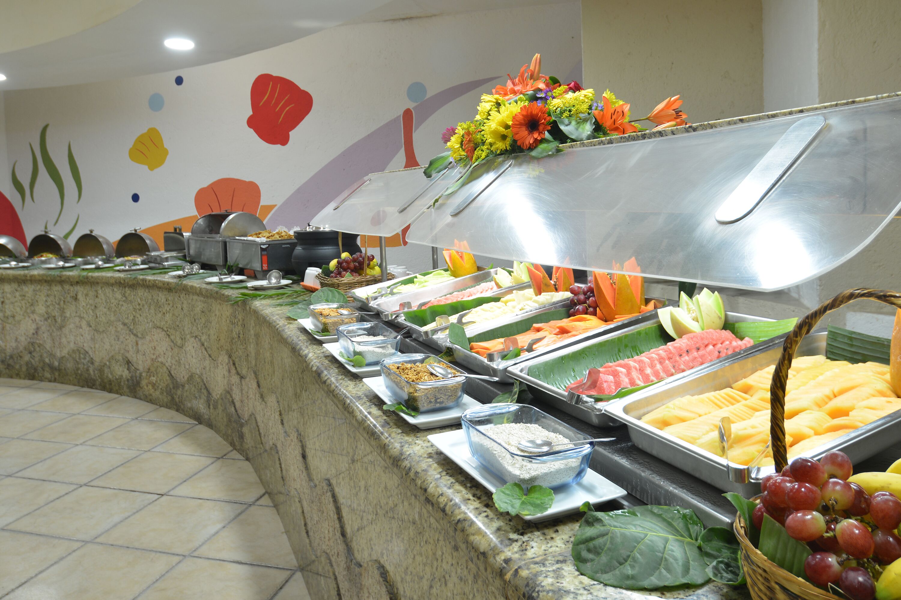 A buffet with various food items and a decorative wall.