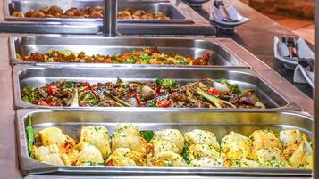 A buffet with various dishes arranged in metal trays.