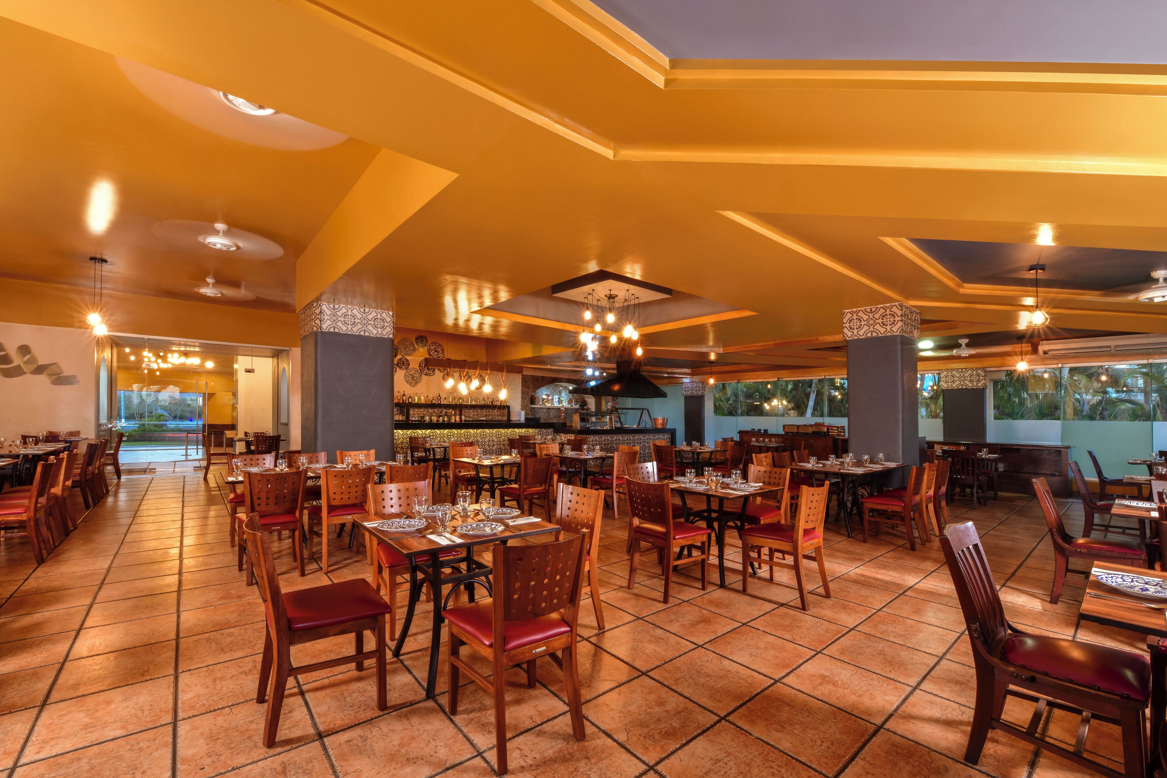 A spacious restaurant with high ceilings, warm lighting, and a variety of seating arrangements.