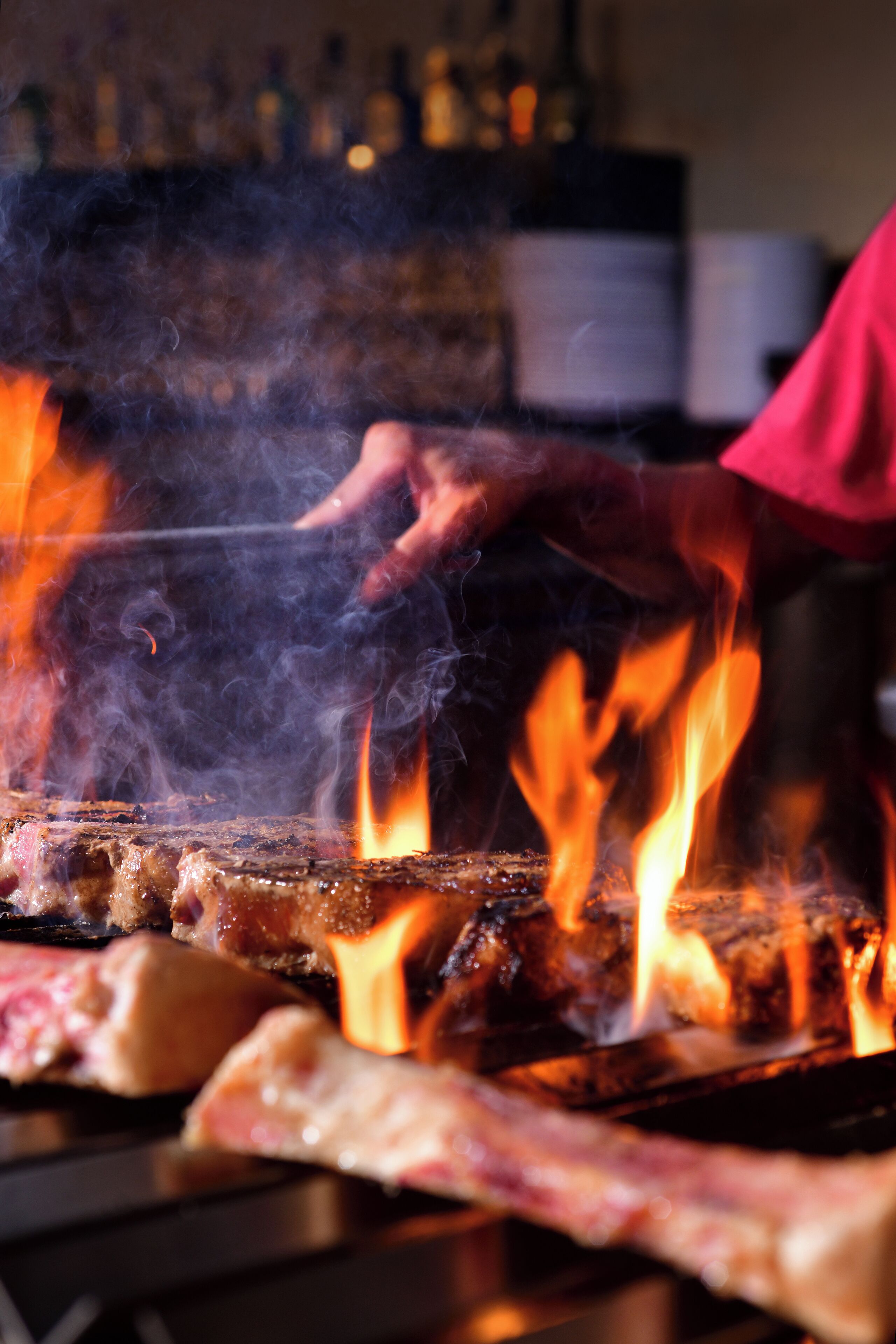 A grill with flames and meat being cooked.