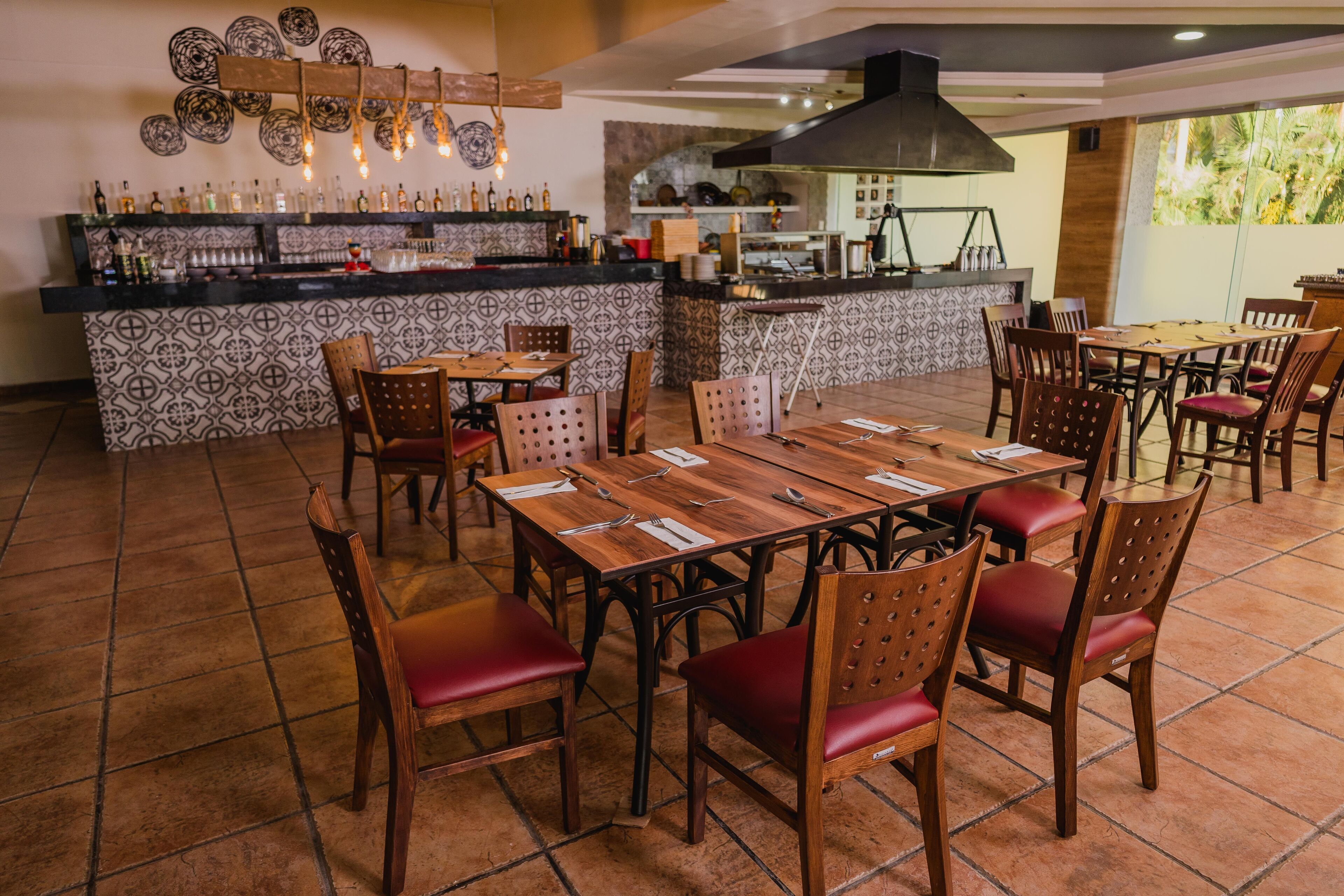 Un restaurante con barra, suelo de baldosas y mesas y sillas de madera.