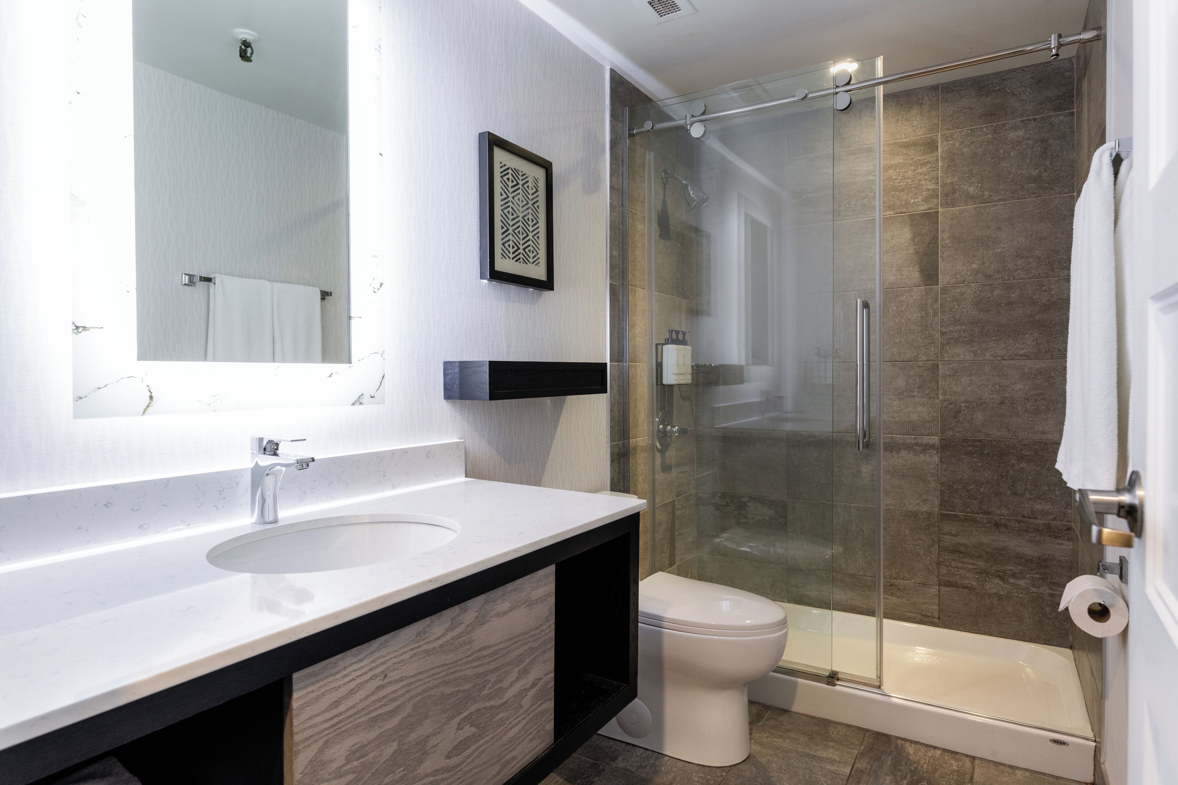 Une salle de bain moderne avec une douche à parois de verre, un lavabo blanc et des toilettes.