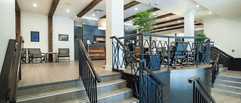 Un moderno vestíbulo de hotel con una escalera, zona de estar y mostrador de recepción.