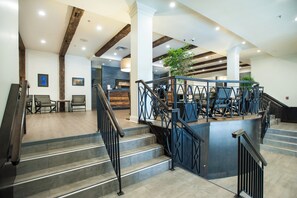 A modern hotel lobby with a staircase, seating area, and reception desk. - Crowne Plaza Moncton-Downtown by IHG (Moncton)