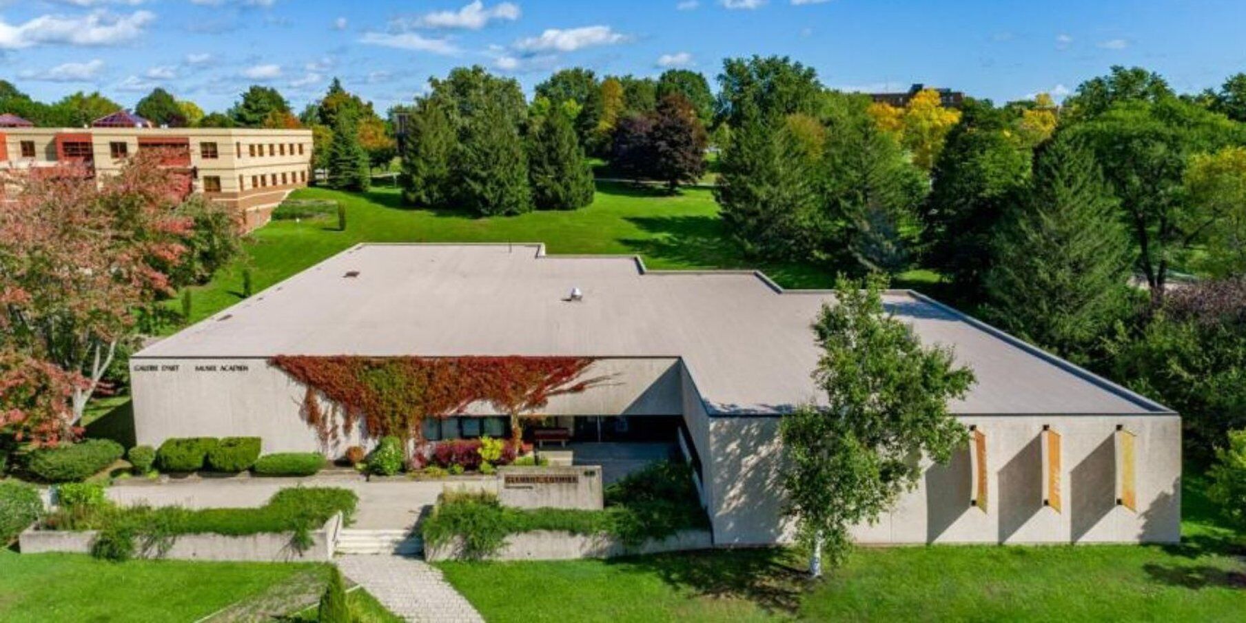 A modern building with a flat roof, surrounded by well-maintained lawns and trees.