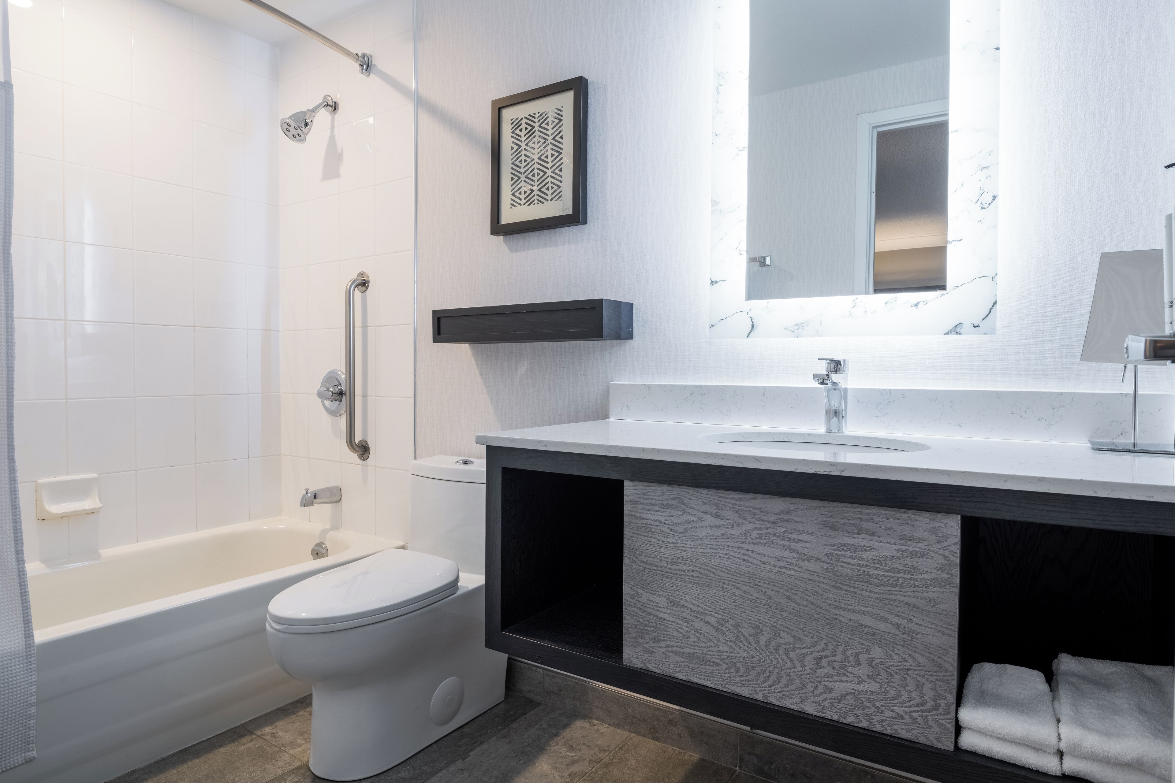 A modern bathroom with a bathtub, toilet, and vanity with a mirror.