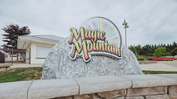 A large rock with the words 'Magic Mountain' on it, surrounded by a stone wall.