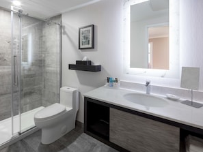 Une salle de bain moderne avec une douche à parois de verre, des toilettes, un meuble-lavabo avec un miroir et un évier.