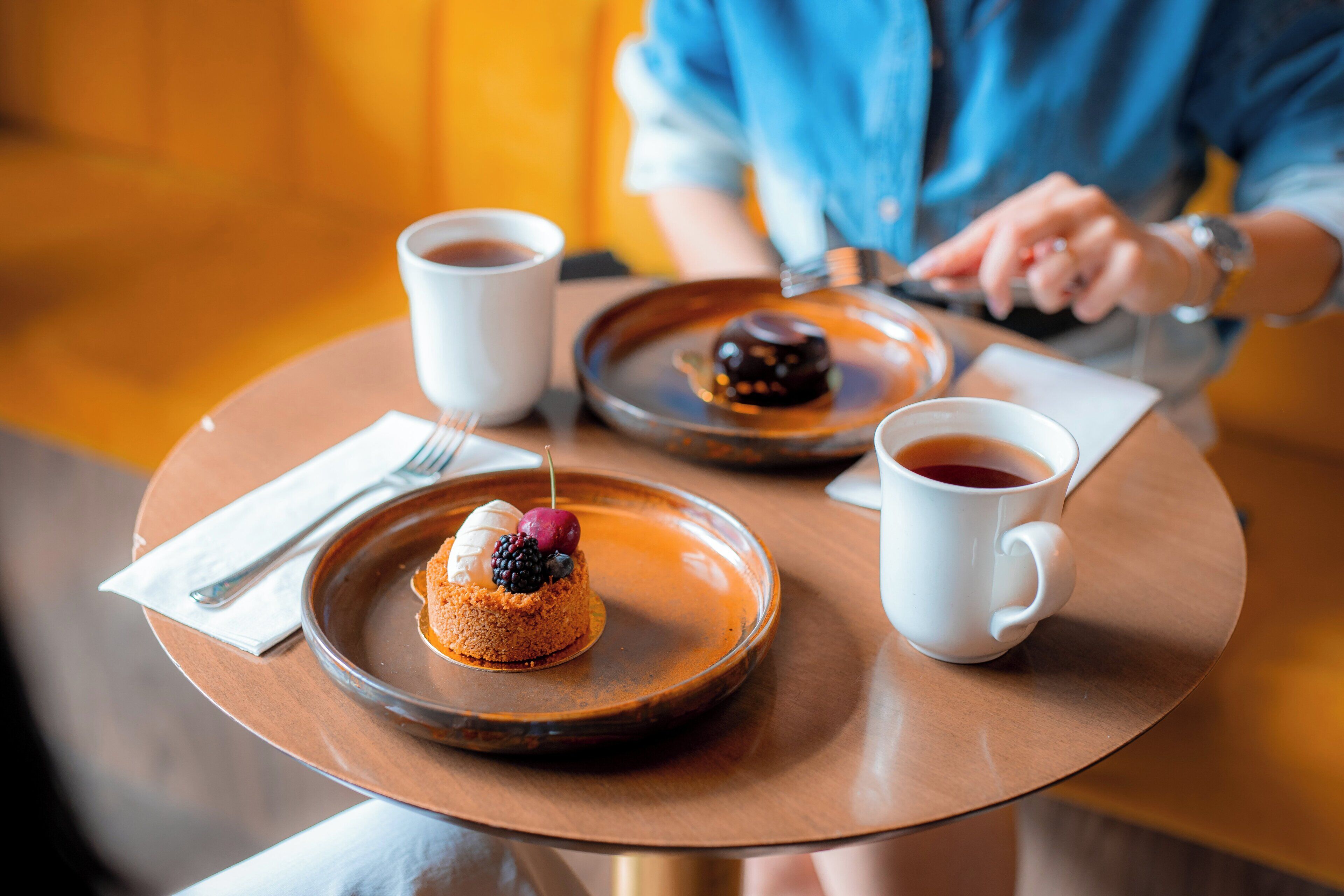 Une table ronde avec une assiette à dessert, deux tasses blanches et une cuillère.
