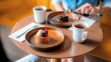 Une table ronde avec une assiette à dessert, deux tasses blanches et une cuillère.
