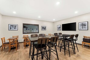 Conference room with a large table and 12 comfortable chairs, featuring a flat-screen TV and artwork on the walls.