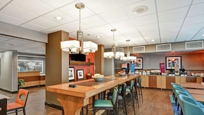 A modern restaurant with a long counter, bar stools, and a variety of seating options. - Hampton Inn Charlotte-Gastonia (Gastonia)