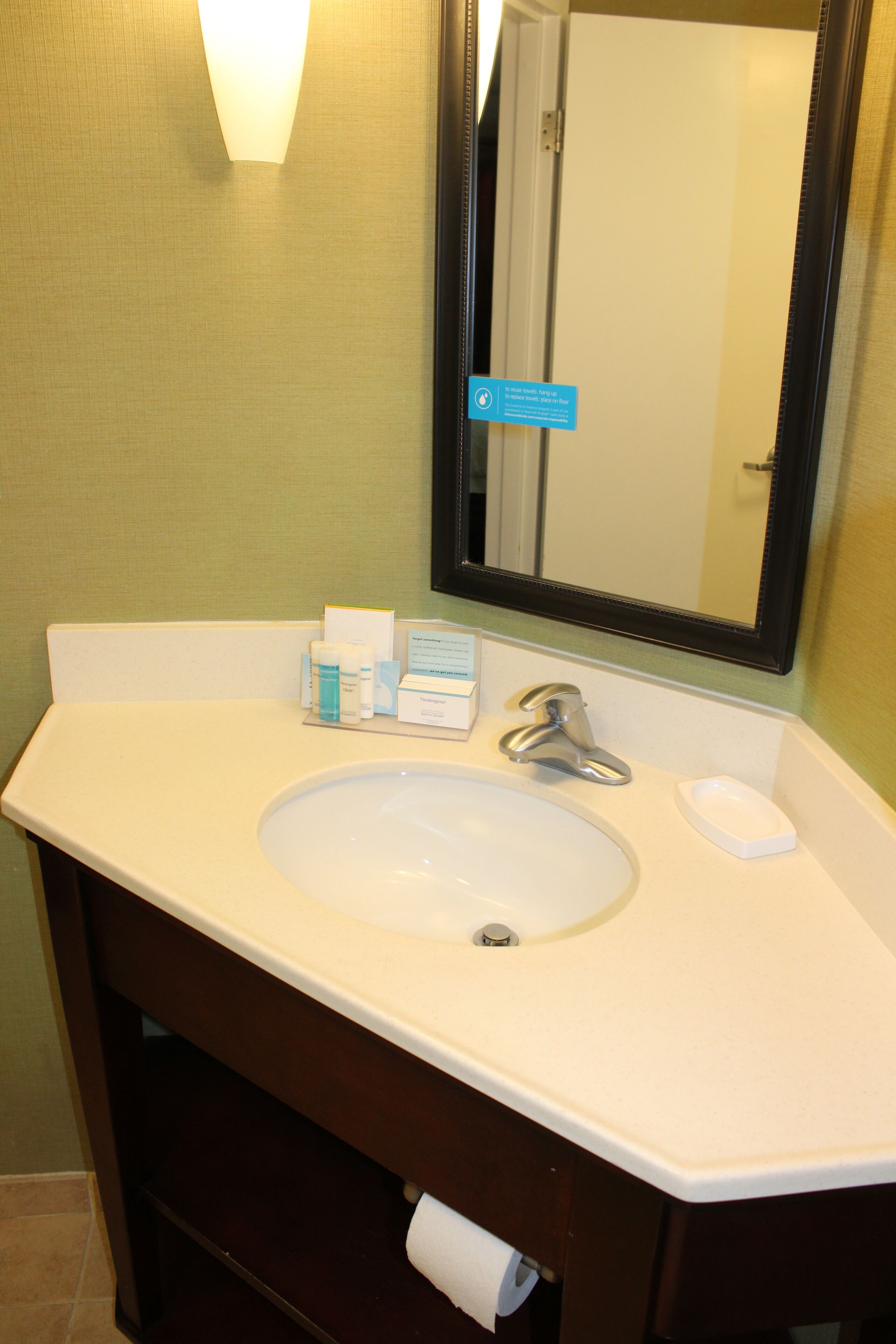 A bathroom with a white sink, a mirror, and toiletries on the counter.
