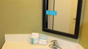A bathroom with a white sink, a mirror, and toiletries on the counter.