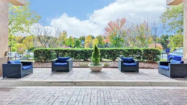 An outdoor seating area with wicker furniture and a central planter. - Hampton Inn Charlotte-Gastonia (Gastonia)