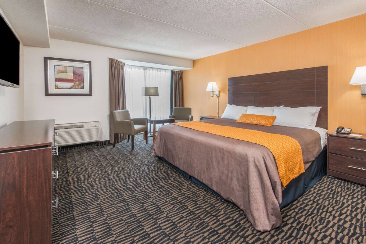 Ein Hotelzimmer mit Bett, Schreibtisch, Stuhl, Lampe und Fernseher.