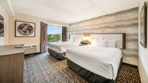 Habitación de hotel con dos camas, un escritorio, un mapa mundial enmarco y vistas al exterior.