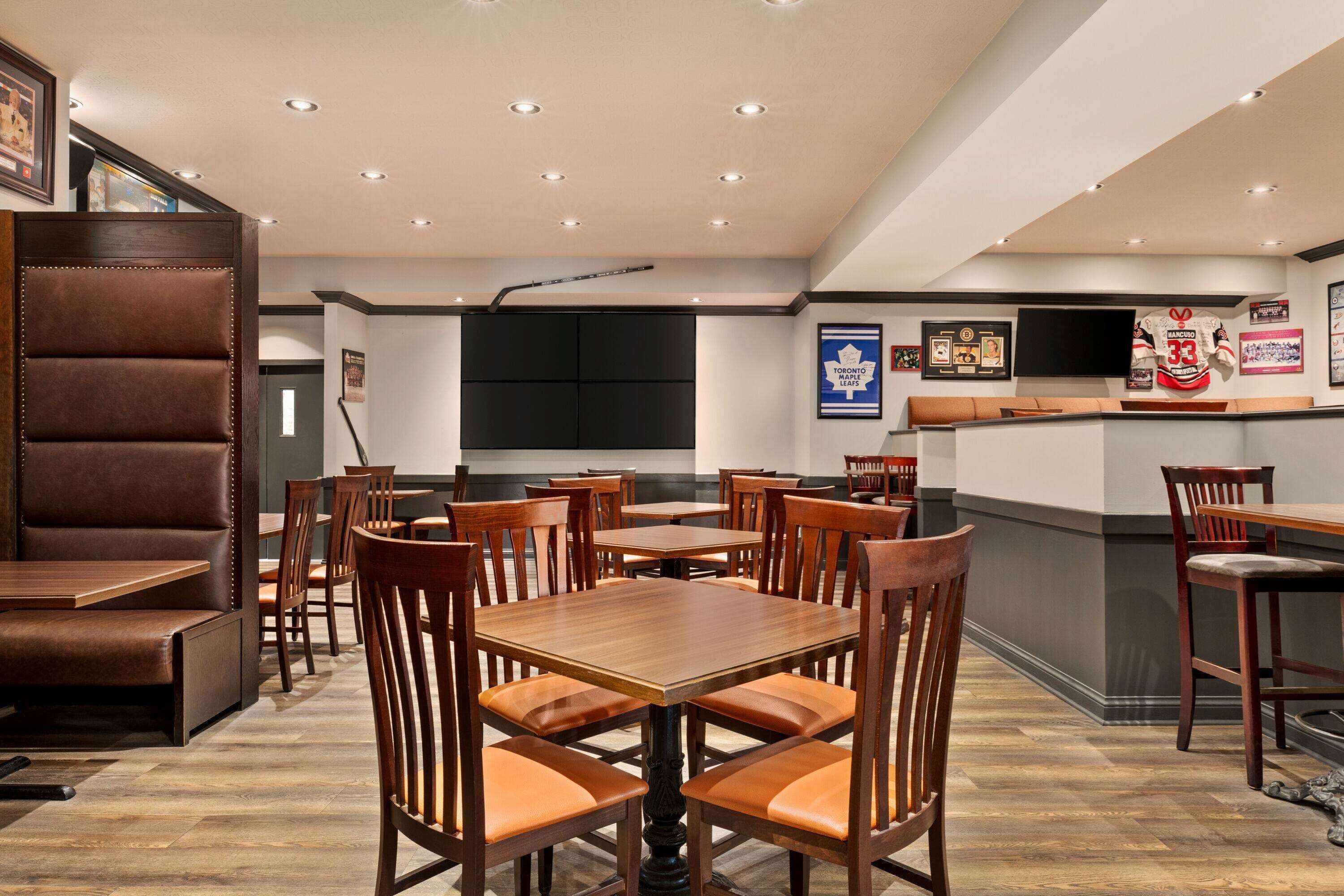 Ein Restaurant mit Holztischen und -stühlen, einer Theke und gerahmten Bildern an der Wand.