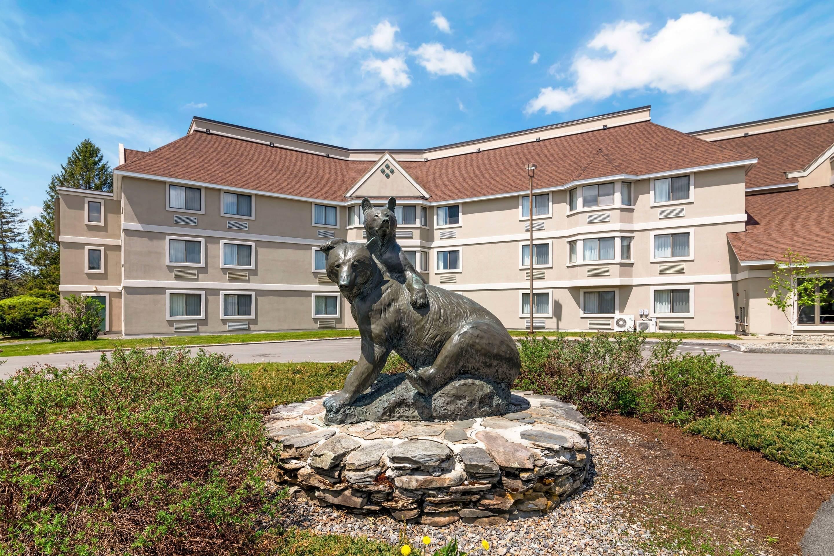 A building with multiple windows and a statue of a bear on a stone base.