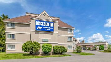 A building with a sign for 'Black Bear Inn Conference Center & Suites' with a clear sky and a well-maintained lawn.
